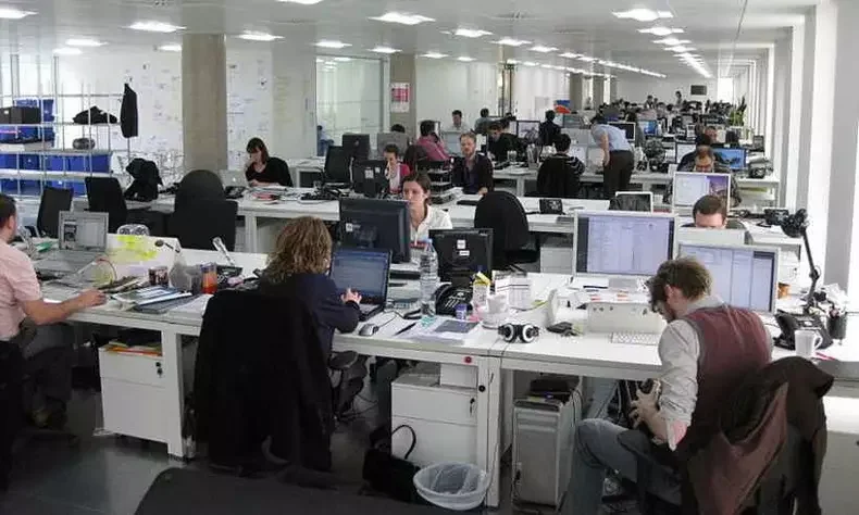 Imagem retrata um escritório com muitos trabalhadores juntos atumultuados, com uma clara desorganização.