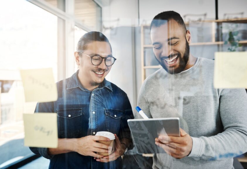 Profissionais analisando informações em um tablet, representando colaboração, tomada de decisão baseada em dados e uso de tecnologia no ambiente corporativo. Imagem que ilustra o uso de dados, tecnologia e colaboração entre equipes para apoiar decisões estratégicas, inovação empresarial e aumento de performance organizacional. Decisões melhores nascem da combinação certa entre dados, tecnologia e pessoas preparadas.